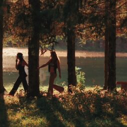 Hippies walking amongst the trees on the shore of a lake